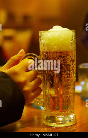 Bier Glas in der Hand Stockfoto