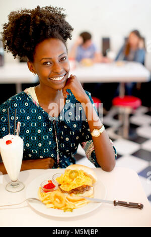 Porträt der jungen afrikanische amerikanische Frau essen im Diner Stockfoto