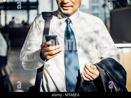 Geschäftsmann mit Handy zu chatten mit Freund nach der Arbeit am Korridor Bürogebäude, selektiven Fokus einerseits und Mobile. Stockfoto