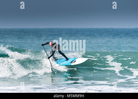 Ein Paddel boarder einer Welle an Fistral in Newquay, Cornwall. Stockfoto