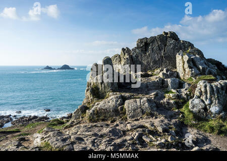 Eine Felsformation aus Granit Felsen an der Küste mit dem Brisons im Hintergrund Cornwall. Stockfoto