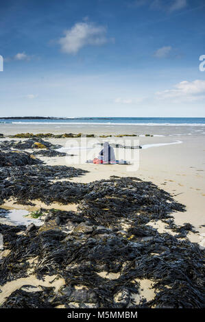 Eine geheimnisvolle Gestalt sitzen am Strand von Sennen Cove in Cornwall. Stockfoto