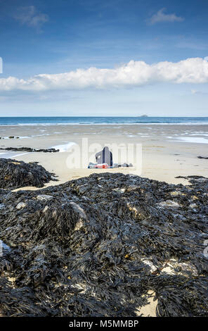 Eine geheimnisvolle Gestalt sitzen am Strand von Sennen Cove in Cornwall. Stockfoto