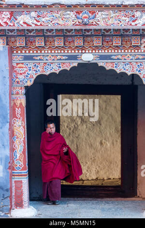 Trongsa, Bhutan. Junger buddhistischer Mönch durch Eingang in den ersten Hof des Trongsa Dzong (Monastery-Fortress), von innen gesehen Stockfoto