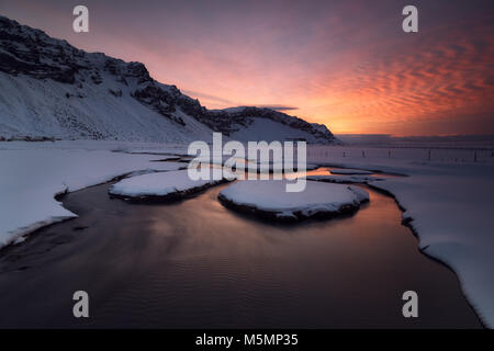 Sonnenaufgang über einem Fluss geschneit in Island Stockfoto