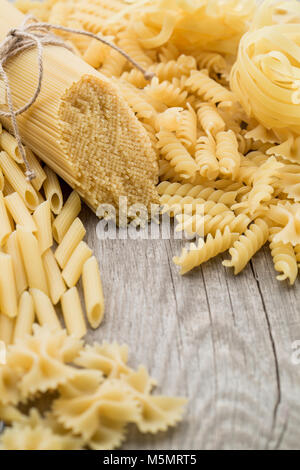 Spaghetti, Farfalle, Fusilli und tortiglioni liegen auf einem alten Holztisch. Platz für Text. Stockfoto