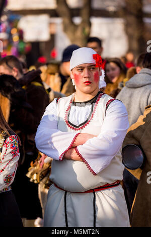 PERNIK, Bulgarien - 26. JANUAR 2018: Junger Mann mit bemalten Wangen rot und gefälschte rote Nelke kreuzt seine Arme an der jährlichen Internationalen Festivals Stockfoto