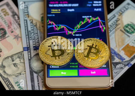 Kaufen und auf Anwendungen von Smartphone mit zwei goldenen Bitcoin auf us-Dollar verkaufen. Stockfoto