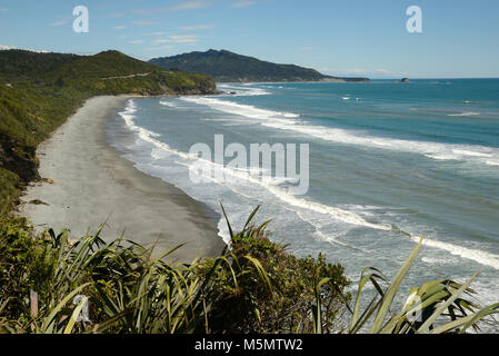 Native Bush Frames ein Strand bei Ebbe auf dem West Coast Beach, South Island, Neuseeland Stockfoto