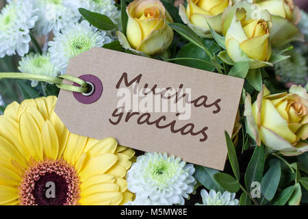 Blumenstrauß aus gelben und weißen Rosen, Gerberas, Chrysanthemas und Grußkarte mit spanischem Text: Danke Stockfoto