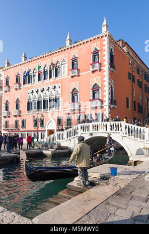 Mann mit einem für eine Gondel außerhalb des Hotel Danieli Riva degli Schiavoni, San Marco, Venedig, Italien Greifer das Boot wie die Tour zu sichern Stockfoto