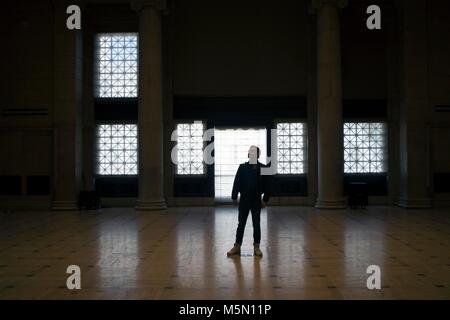 Ein Mann steht in der Mitte der Ballsaal im Museum für Asiatische Kunst in San Francisco. Stockfoto