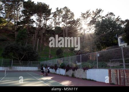 Zwei Personen bereiten Tennis unter die Sonnenstrahlen durch die Bäume in San Francisco zu spielen. Stockfoto