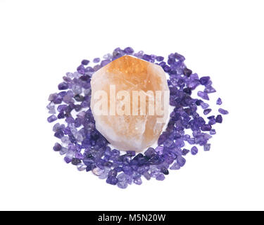 Natürliche citrin Punkt umgeben von kleinen Amethyst Trommelsteine Chips auf weißem Hintergrund Stockfoto