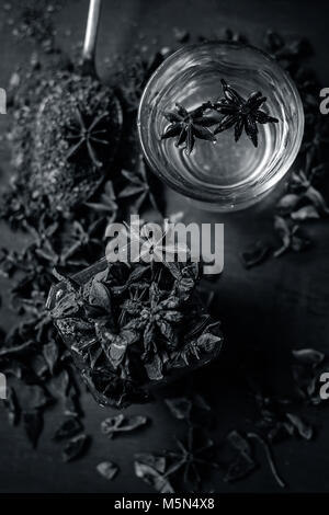 Illicium verum Sternanis Samen in einer Glasschale. sein Pulver und sein Wasser auf Holz- Oberfläche. Stockfoto