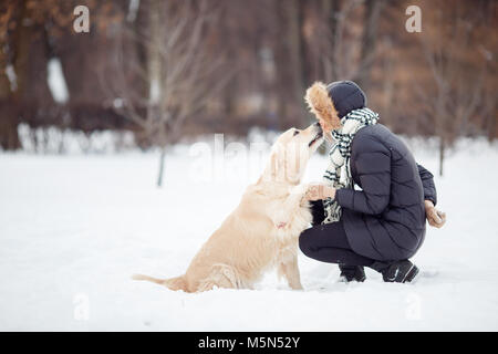 Bild von Mädchen in schwarzen Jacke mit Labrador an snowy Park Stockfoto