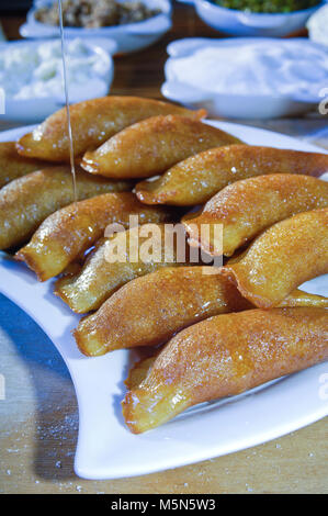 Gießen Sirup auf Qatayef, arabische Süßigkeiten mit Muttern und andere Zutaten für Ramadan und Eid Stockfoto