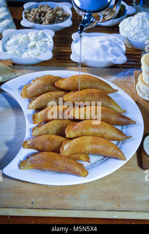 Gießen Sirup auf Qatayef, arabische Süßigkeiten mit Muttern und andere Zutaten für Ramadan und Eid Stockfoto