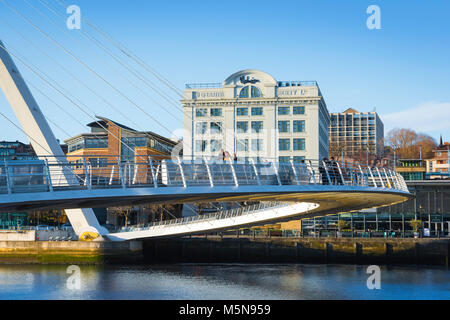 Blick auf junge Menschen, die über die Millennium Bridge mit dem Kai der Stadt von Newcastle upon Tyne im Hintergrund, England, Großbritannien Stockfoto