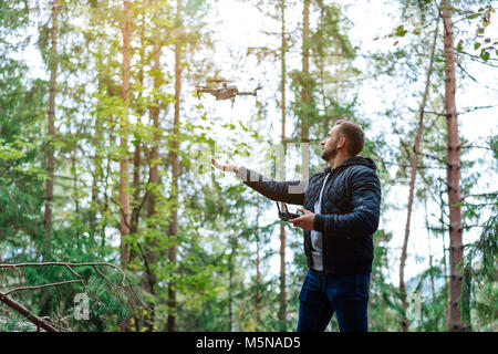 Guy startet einen quadrocopter im Wald Stockfoto