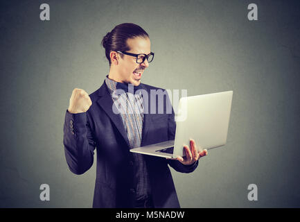 Neugierige junge Mann mit Laptop und suchen gerne gewinnen mit schnell aktualisieren. Stockfoto