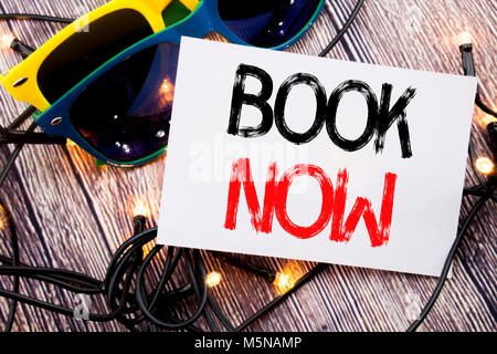 Schreiben text Buchen Sie jetzt zeigen. Business Konzept für Buchung Buchung auf alten Holz Hintergrund mit Sonnenbrille geschrieben Kaufen Stockfoto