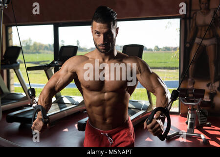 Gut aussehend muskuläre Fitness Bodybuilder schwere Übung für Brust auf Rechner mit Kabel In der Turnhalle Stockfoto