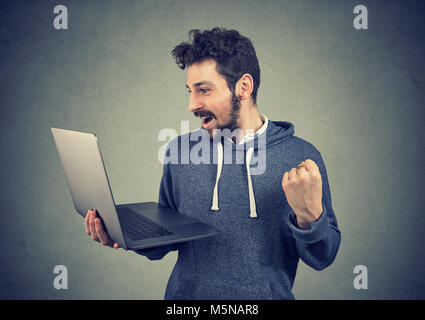 Neugierige junge Mann mit Laptop und suchen gerne gewinnen mit schnell aktualisieren. Stockfoto