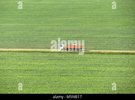 Lkw fährt auf der Straße auf ein grünes Feld. Die ländliche Landschaft mit Straßen- und Lkw, Ansicht von oben Stockfoto