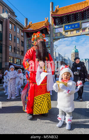 Ein Darsteller gekleidet wie Caishen, dem Chinesischen Gott des Reichtums, Wohlstand, Glück, und kleine Mädchen wie ein Hund, chinesische Mondjahr Parade, Chinato Stockfoto