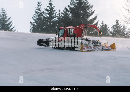 Red snowcat auf Schnee im Winter in die Berge. Ratrack Verbesserung oder Aufrechterhaltung einer Skipiste. Schneit. Stockfoto