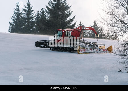 Red snowcat auf Schnee im Winter in die Berge. Ratrack Verbesserung oder Aufrechterhaltung einer Skipiste. Schneit. Stockfoto