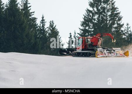 Red snowcat auf Schnee im Winter in die Berge. Ratrack Verbesserung oder Aufrechterhaltung einer Skipiste. Schneit. Stockfoto