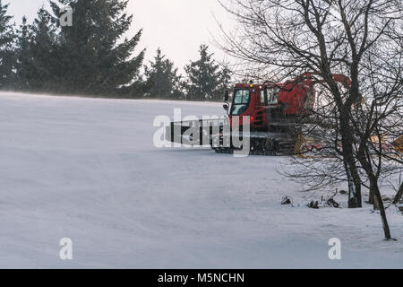 Red snowcat auf Schnee im Winter in die Berge. Ratrack Verbesserung oder Aufrechterhaltung einer Skipiste. Schneit. Stockfoto