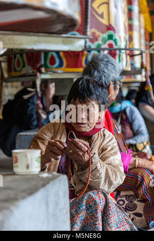 Thimpu, Bhutan. Anbeter mit ihrem Gebet Brads unterhalb einer Gebetsmühle am National Memorial Chorten. Stockfoto