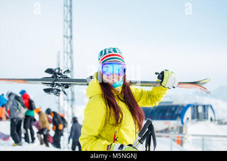 Bild von lächelnden Sport Frau mit Skier auf die Schulter auf dem Hintergrund von Snow Hill, Menschen im Winter Stockfoto