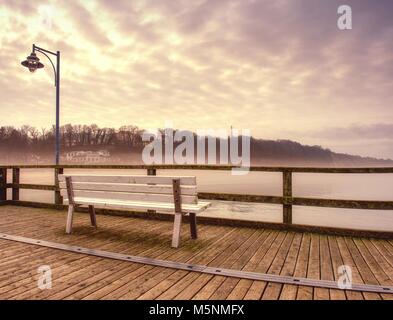 Misty Dämmerung auf das Wahrzeichen Angelpier, hölzernen Pier Geländer. Holz- Mole endet in dichten Nebel Stockfoto