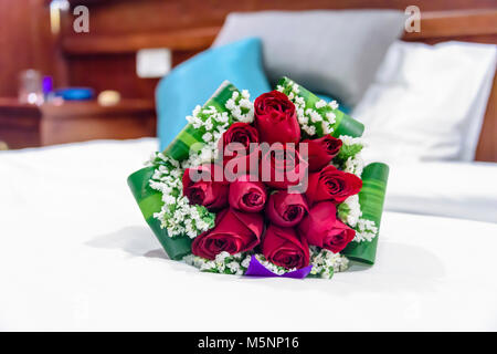 Ein Strauß roter Rosen liegen auf einem Bett. Stockfoto
