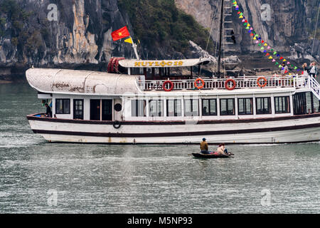 Touristische Passagier Kreuzfahrt Schiff segelt vor zwei Fischer in einem kleinen Boot in der Halong Bay, Vietnam Stockfoto