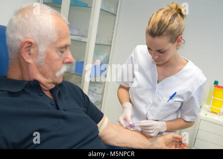 Krankenschwester Zeichnung Blutprobe von älteren männlichen Patienten Stockfoto