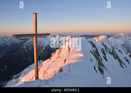 Sonnenuntergang auf dem Gipfel des Tauberspitze (Lechtaler Alpen) im Winter mit Gipfelkreuz. Tirol, Österreich Stockfoto