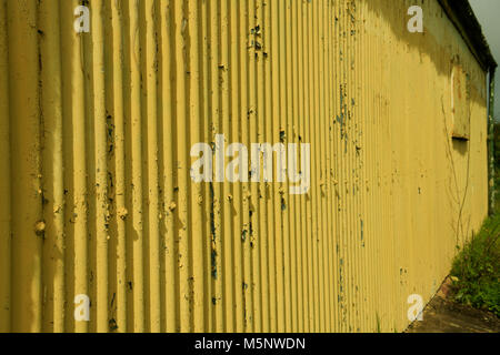 Grunge, vertikale Linien der vernachlässigten gelbe Wand mit der Farbe abblättern Stockfoto