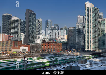 Pendler gehen Züge auf Bahnstrecken in Toronto mit stadtbild Skyline von hochhäusern an der Vorderseite und Spadina im Winter Stockfoto