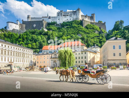 Historische Stadt Salzburg mit traditionelle Pferdekutschen Fiaker Beförderung und der berühmten Festung Hohensalzburg im Sommer, Österreich Stockfoto