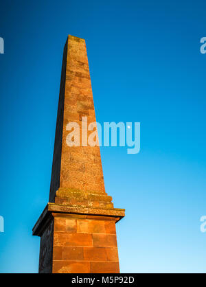 Blaikie Heugh East Lothian, Schottland, Vereinigtes Königreich, 25. Februar 2018. Völlig klaren blauen Himmel mit geringer Sonneneinstrahlung von der untergehenden Sonne leuchtet auf dem Hügel obelisk Balfour Monument, einem Denkmal für James Maitland Balfour, die Konservative in den 1840er Jahren, und der Vater von Premierminister Arthur Balfour, 1 Graf von Balfour. Der zunehmende Mond ist sichtbar in den strahlend blauen Himmel Stockfoto