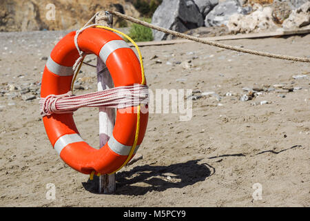 Schwimmweste am Sandstrand irgendwo nahe am Meer Stockfoto