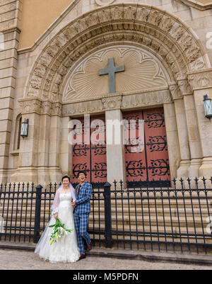 China, Provinz Shandong, Qingdao, junges Ehepaar vor der Kathedrale St. Michael in der Altstadt. Stockfoto