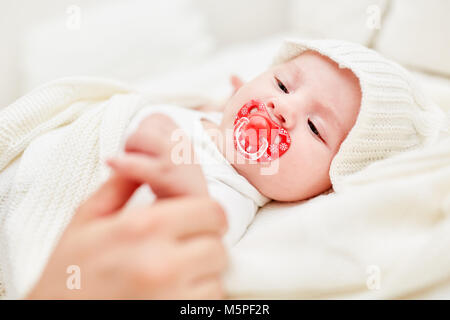 Neugeborenes Baby mit schnuller Zupacken der Daumen eines Erwachsenen Stockfoto