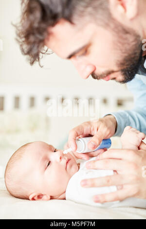 Sick baby Nasenspray für kalte von gesorgt Vater Stockfoto