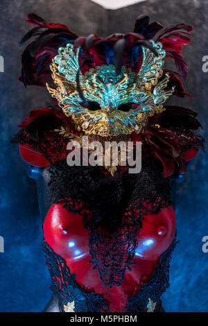 Maskerade Partei in venezianischem Rot, Maske und roten Korsett mit Stücken von Gold und schwarze Spitze Stoffen auf Metall Schild. Handgefertigte piea für Partys oder costu Stockfoto
